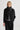 Person wearing a black coat, gray scarf, and dark pants on a white background