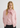 Woman wearing a pink sweater and scarf against a white background
