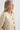 Woman wearing a beige cardigan with buttons on a white background