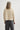 Person wearing a beige sweater and gray pants on a white background
