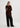 Person wearing a brown sweater and black pants on a white background