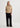 Person wearing a beige sweater and black pants on a white background