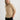 Woman wearing a beige sweater and black pants against a white background