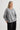 Woman wearing a gray sweater and black pants on a light gray background