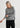Woman wearing a gray sweater and black pants on a white background