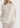Woman wearing a cream sweater and pants on a white background