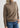 Woman wearing a brown turtleneck sweater and blue jeans on a white background