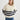 Woman wearing a cream sweater with navy stripes and blue jeans on a white background