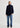 Person wearing a navy sweater and blue jeans on a white background