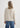 Person wearing a beige sweater and blue jeans on a white background