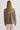 Person wearing a brown sweater and white pants on a plain background