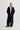 Person wearing a long navy coat on a white background