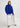 Person wearing a blue sweater and white pants on a light gray background
