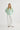 Person wearing a light green sweater and white pants on a white background
