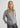 Woman wearing a gray turtleneck sweater and pants on a light gray background