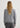 Person wearing a gray sweater and pants on a white background