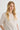 Woman wearing a white sweater against a plain background
