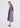 A woman modeling a long-sleeve midi dress with vertical red, blue, and white stripes, standing against a plain white studio background.
