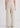 A model shown from the back wearing high-waisted, wide-leg trousers in a light beige or cream color, paired with a matching top against a plain light gray studio background.