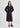 A woman modeling a black wrap midi dress with voluminous long sleeves and a self-tie waist, paired with brown platform sandals, against a light gray studio background.