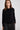 Woman wearing a black sweater and dark pants against a white background