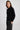 Woman wearing a black sweater and pants against a white background